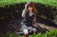 一位红发年轻女子穿着黑色连衣裙，坐在户外