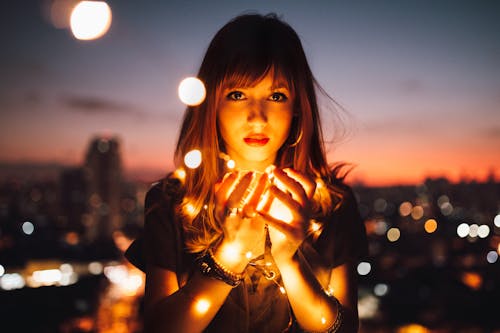 Mujer madura con luces románticas en ciudad