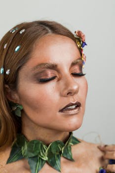 Stunning portrait of a woman with closed eyes, features artistic leaf makeup and gemstones.