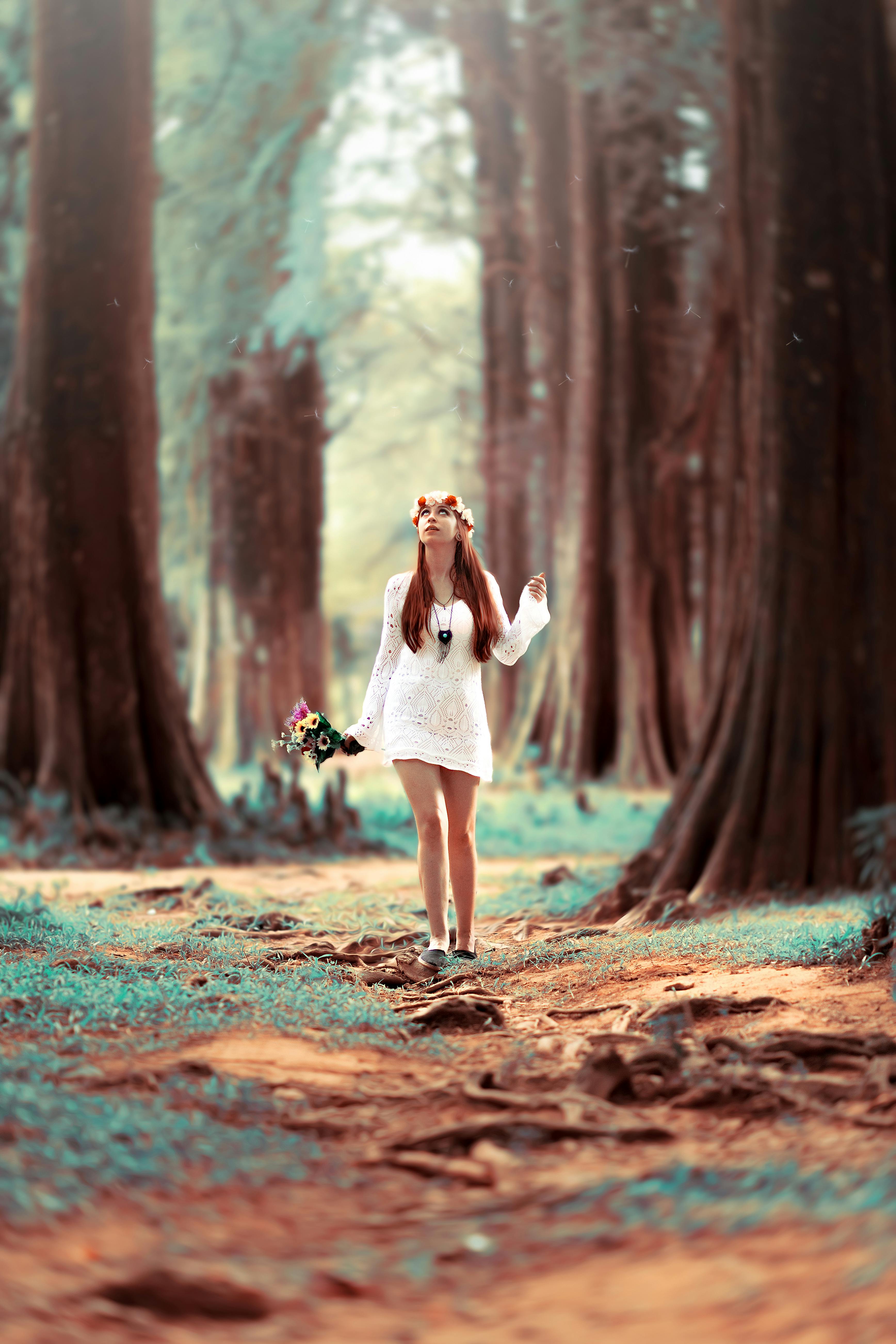 woman carrying flowers while standing at woods