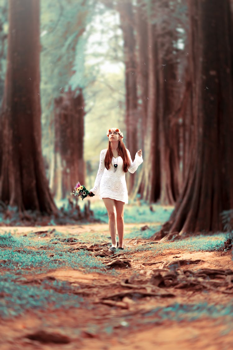 Woman Carrying Flowers While Standing At Woods