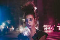 夜色中，一位卷发的年轻女子举着灯光，营造出梦幻般的氛围