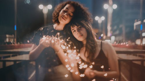 Free Selective Focus Photography of Two Women Holding String Lights Turned on Stock Photo