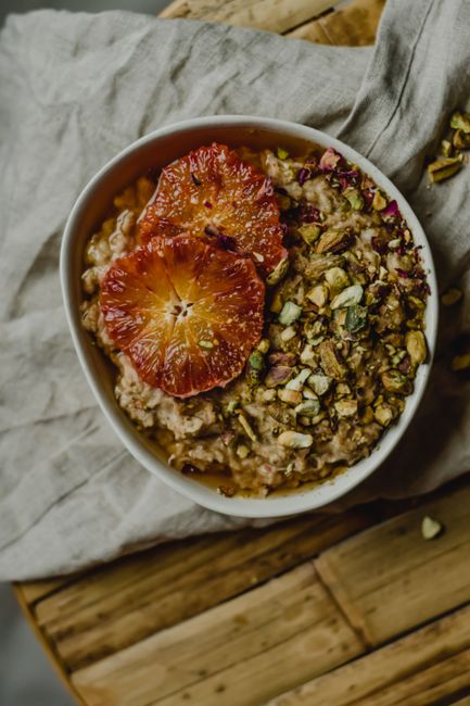 A bowl of thick, creamy oat porridge topped with sliced banana, a drizzle of honey, and a sprinkle of cinnamon.