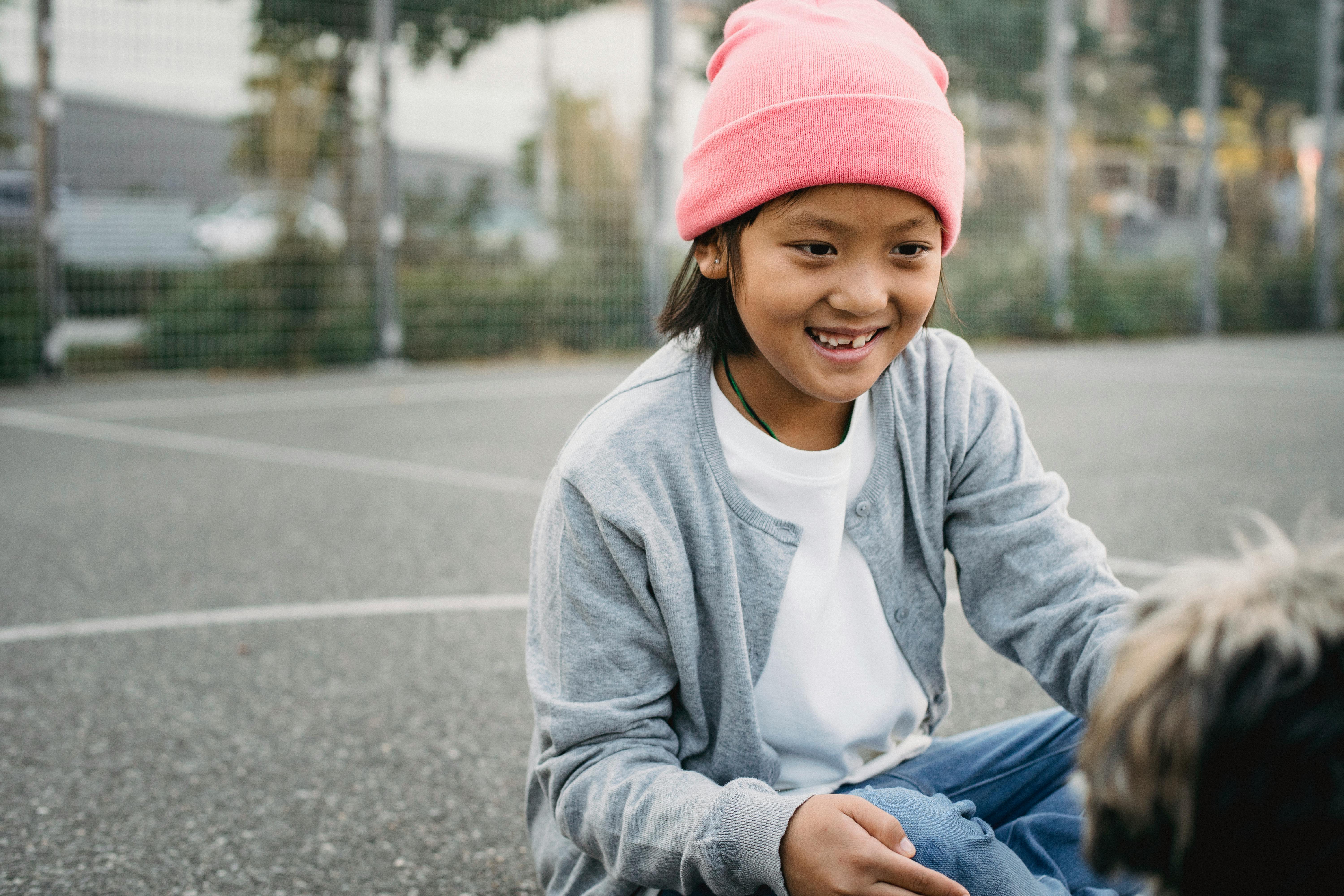 smiling asian boy with dog on sports ground