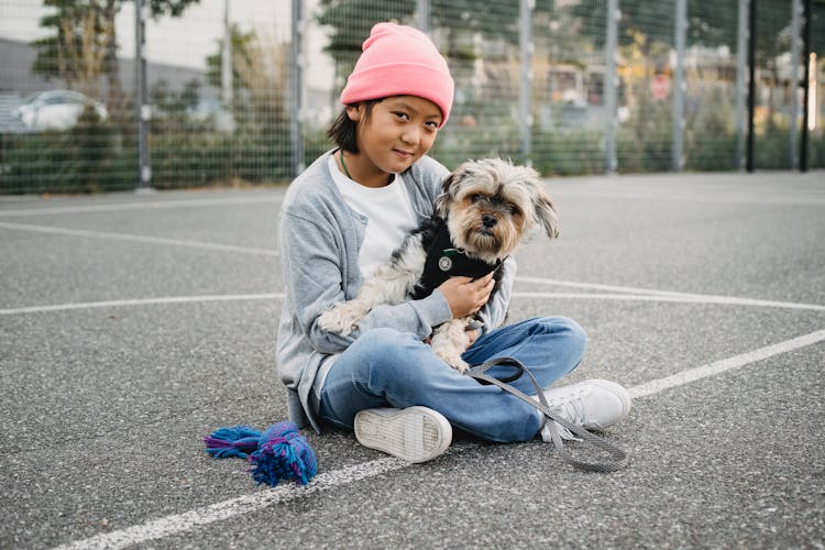 Charming Asian Boy With Yorkshire Terrier On Sports Ground