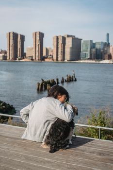 孩子在平静的河流边放松时，拥抱小狗的背影已面目全非