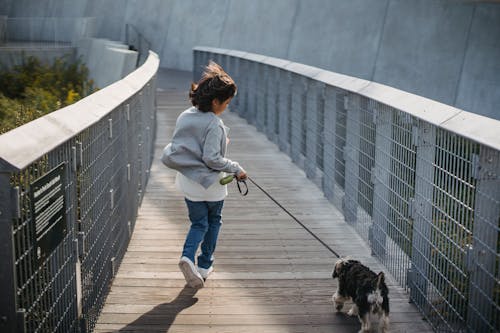 Anonymous kid running with dog on leash