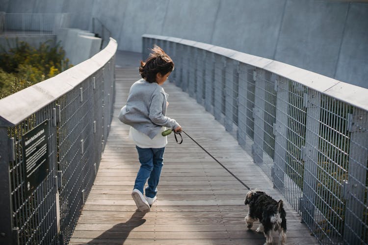 Anonymous Kid Running With Dog On Leash