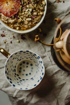 Overhead view of a breakfast setup with porridge, coffee, and a dotted cup on rustic fabric.