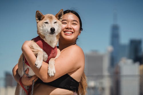 Happy Asian woman cuddling cute dog