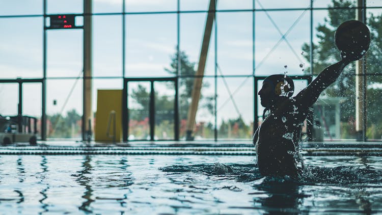 Man Throwing A Ball While On The Pool