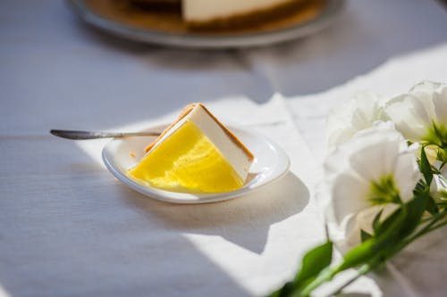 Tasty cheesecake near decorative flowers on table