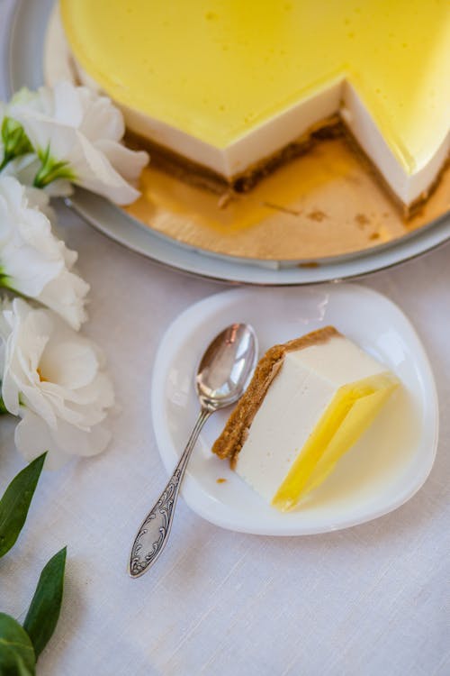 From above of delicious piece of cheesecake with colorful gelatin on top on saucer with spoon