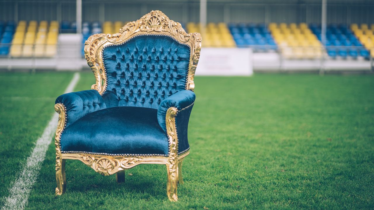 a luxurious blue velvet and gold armchair sits prominently on a sports