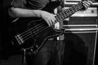 Crop guitarist playing electric bass guitar during rehearsal