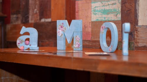 Blue decorative letters forming word love in Spanish arranged on wooden shelf in living room