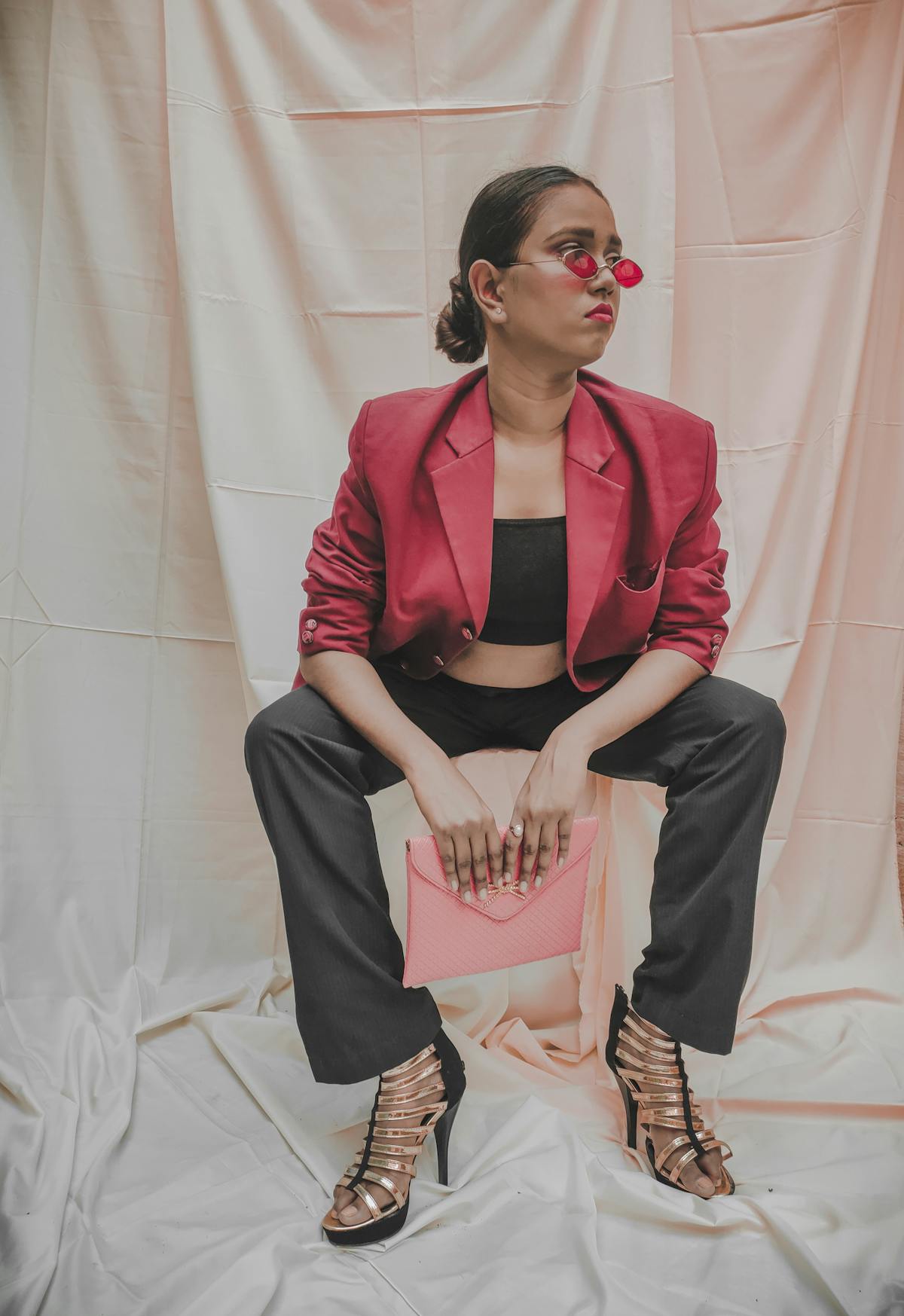 Donna con blazer rosso, pantaloni neri e clutch rosa in studio