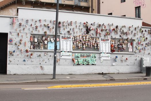 Colorful dolls displayed on an outdoor wall in Milan's art district.
