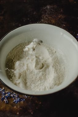 Pó branco em tigela branca sobre superfície rústica escura — bicarbonato de sódio para uso culinário