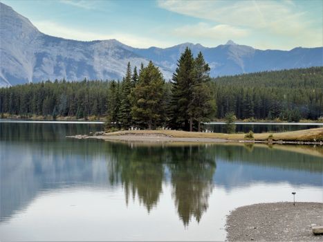 Peaceful mountain lake with conifer reflection in Alberta, Canada. Calm and picturesque spring scene.