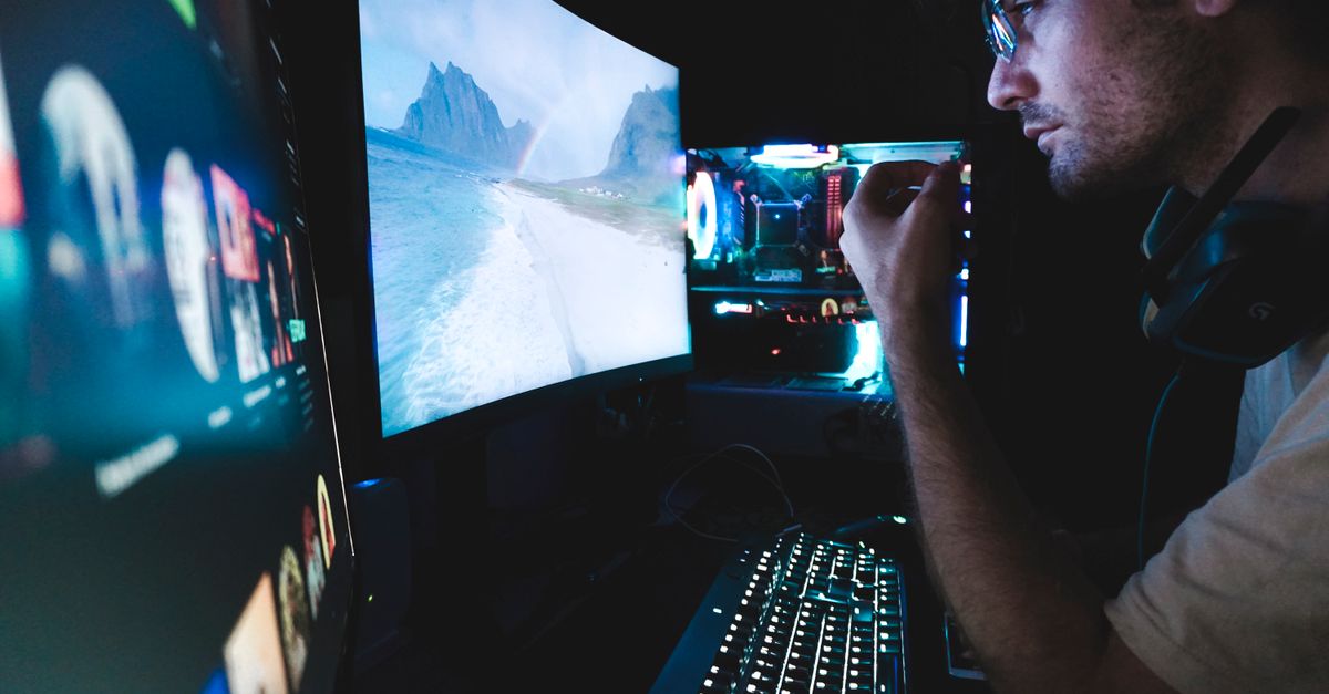 A man in eyeglasses focused on multiple screens, showcasing modern technology setup.