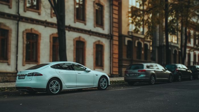 Side view of a sleek white sedan parked on a quiet urban street — photo by Borta on Pexels