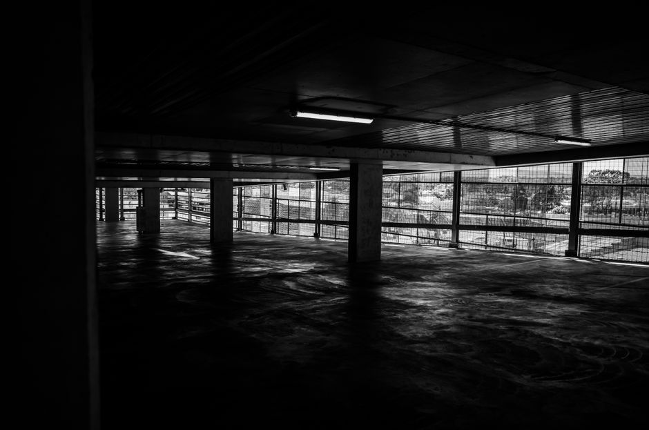 Dark and empty abandoned parking garage captured in a black and white photograph.
