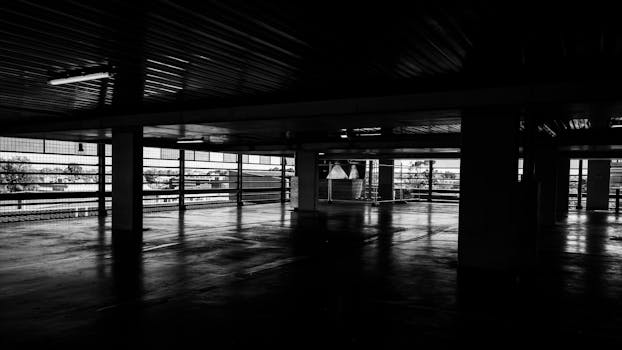 Moody black and white depiction of an empty urban multi-story parking garage.