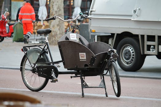 Close-up of a classic cargo bike parked on a city street with urban elements in the background.