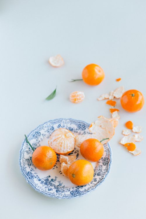 Free High-angle view of fresh mandarin oranges on a decorative ceramic plate with peels. Stock Photo