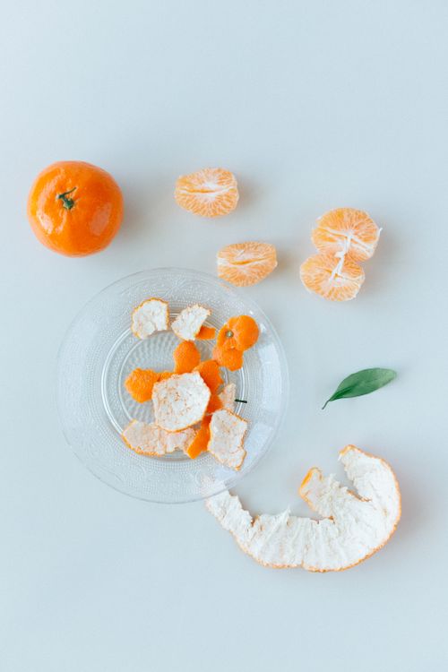 Free Vibrant mandarin oranges with peel on a clear glass plate against a white surface. Stock Photo
