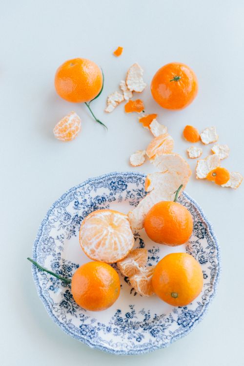 Free Top view of vibrant mandarins on a floral ceramic plate with a light background. Stock Photo