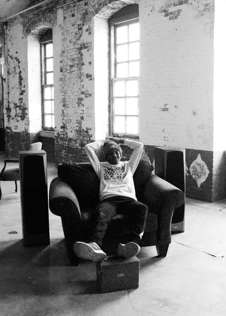 Trendy Black Man Resting In Armchair In Old Building