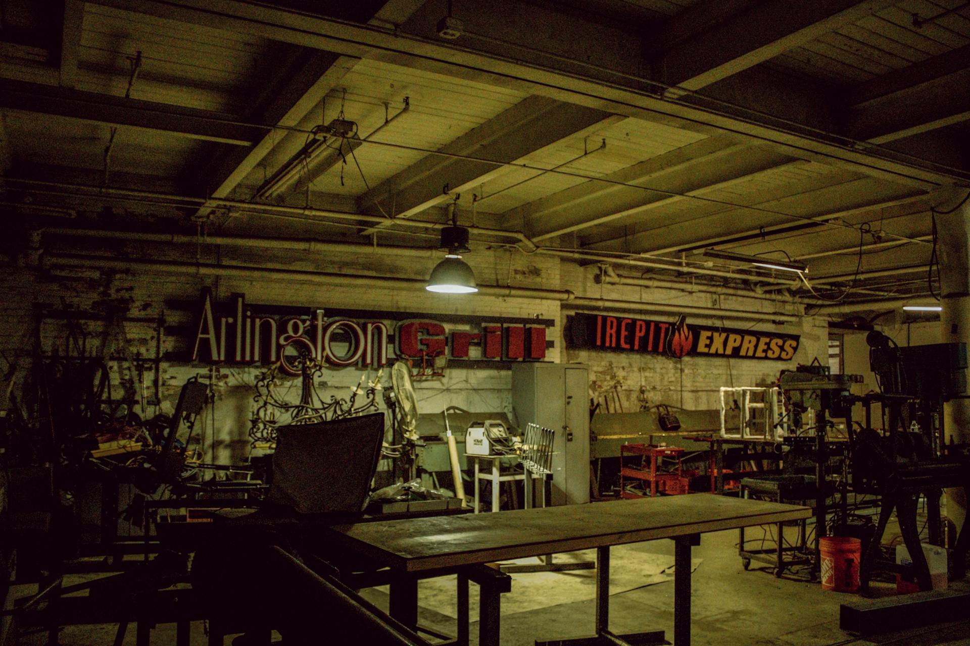 A dimly lit industrial workshop with vintage signs and metal machinery.