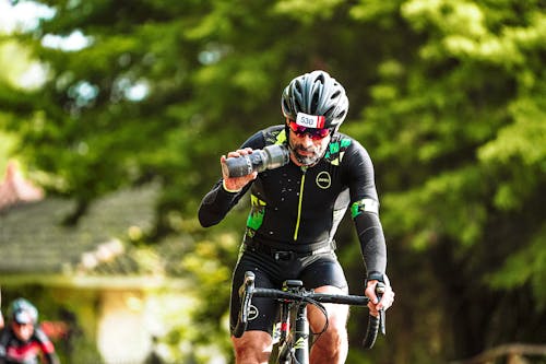 Adult cyclist drinking water while riding bicycle