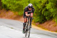 Concentrated man in helmet riding bike on paved road