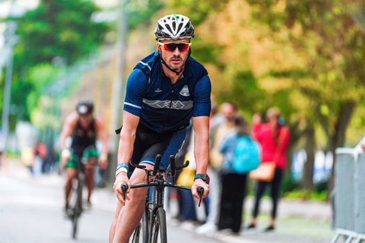 A determined male cyclist competing in an outdoor road race, showcasing focus and speed.