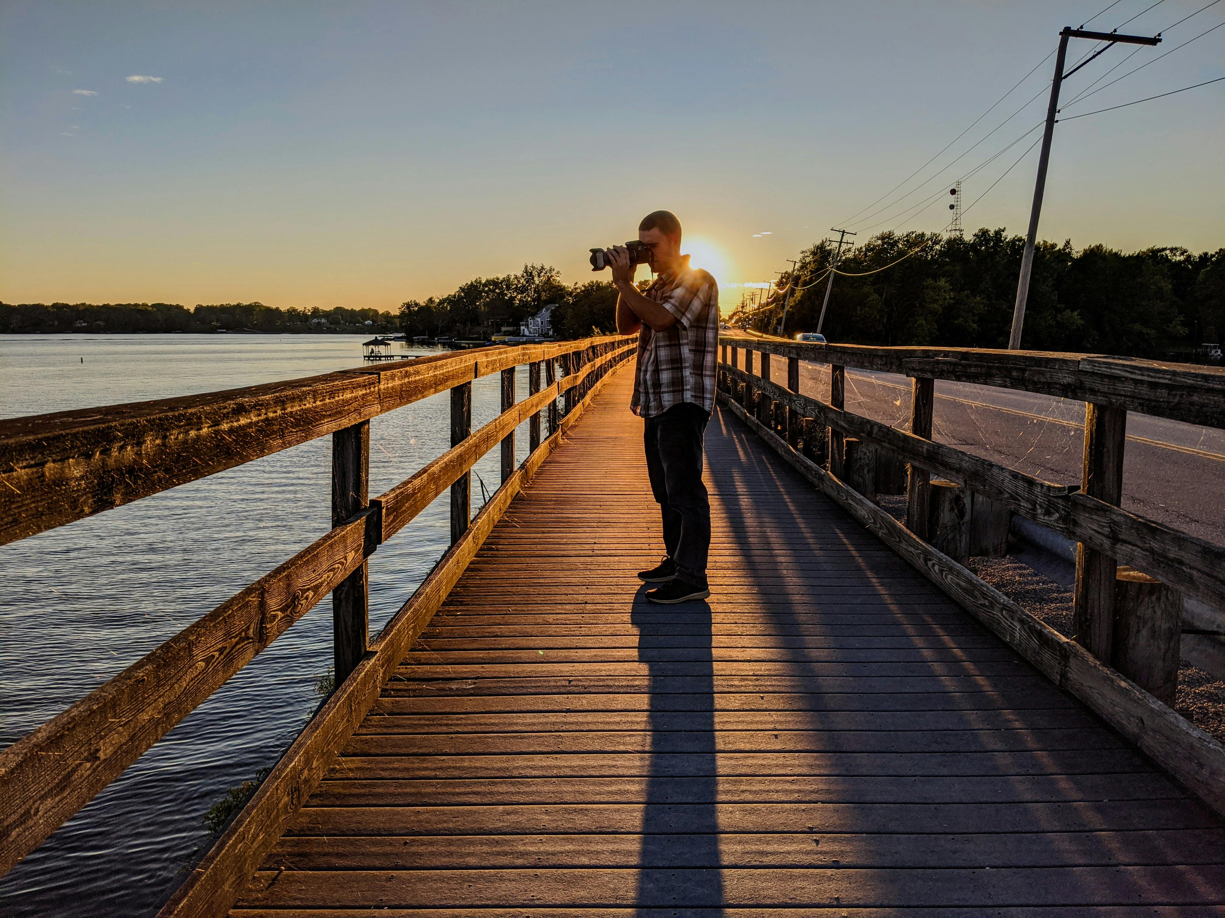 A man takes photos on a bridge during sunset at Lake Milton, Ohio.