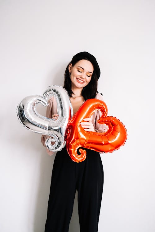 Woman in Black Dress Holding Heart Shaped Balloons