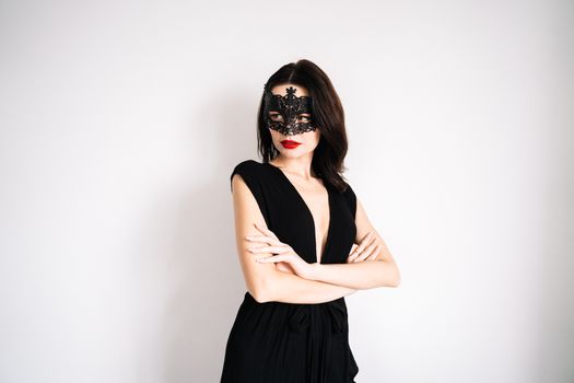 一位身着黑色连衣裙、戴着面具的老练女性在工作室里优雅地摆着姿势