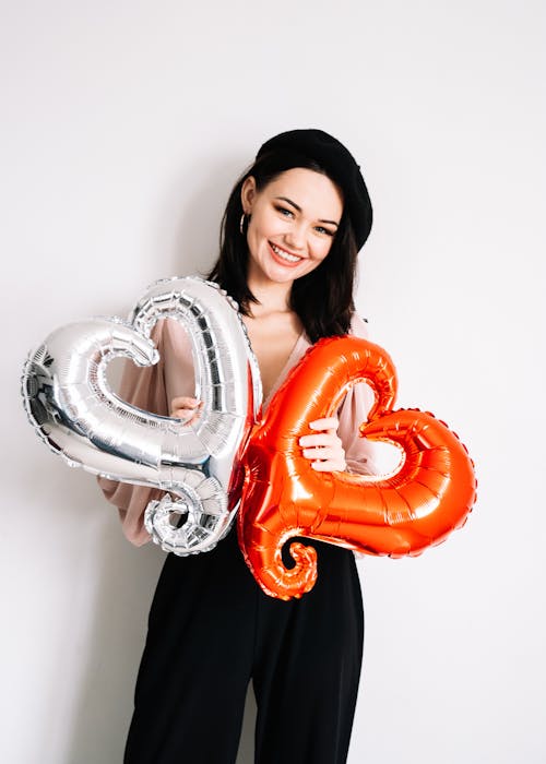 Woman in Black Pants Holding Heart Shaped Balloon