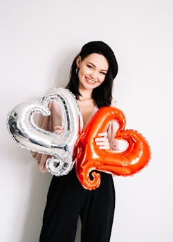 迷人的妇女为情人节庆祝活动与心形气球摆姿势