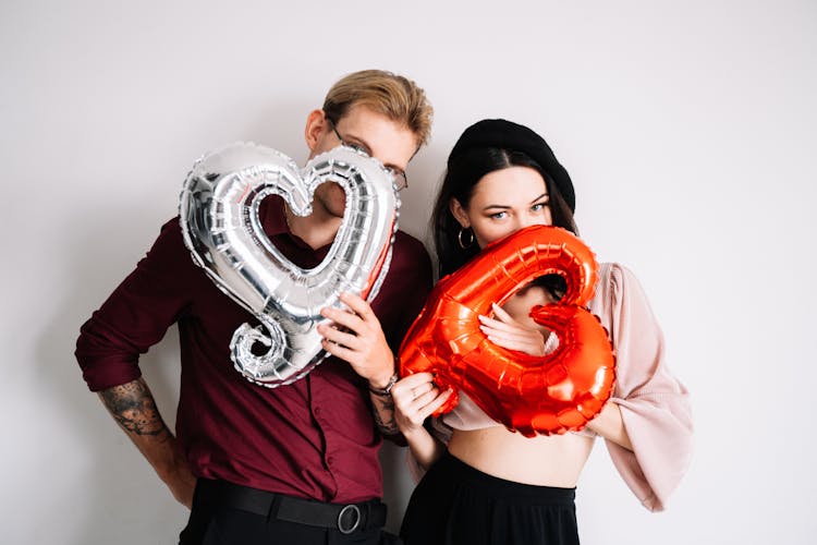 A Man And A Woman Holding Heart Shaped Balloons