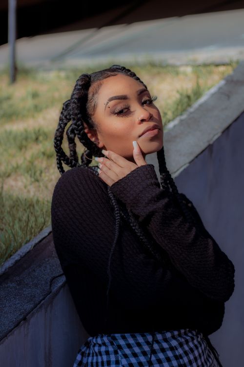 Free A fashionable young woman posing outdoors in a stylish outfit with braided hair and thoughtful expression. Stock Photo