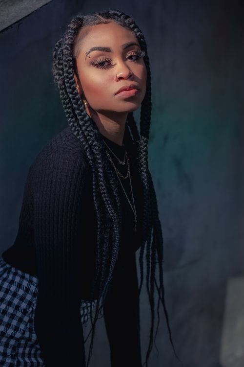 Free Elegant portrait of a young woman with braided hair in stylish black attire. Stock Photo