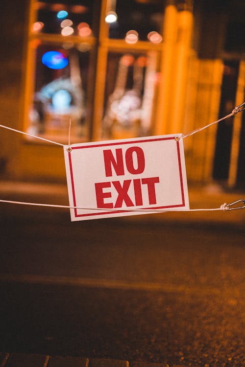 Bright restricting sign saying no exit hanging on road of city at night