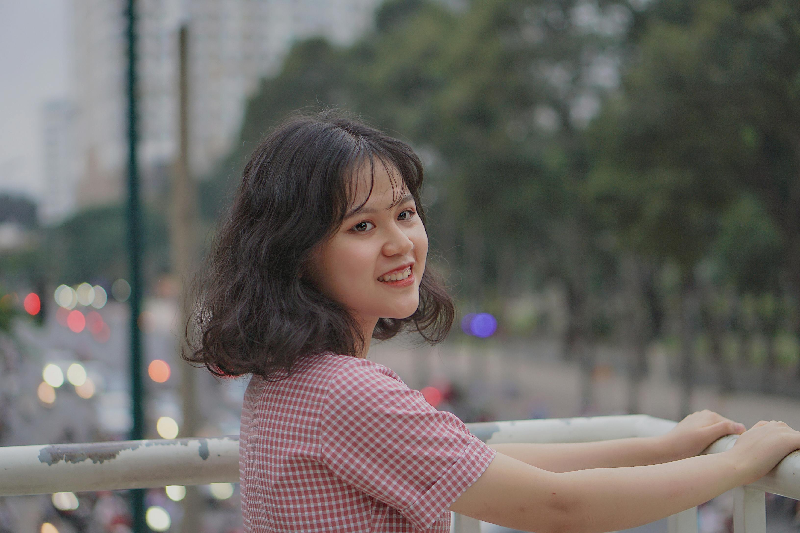 Young woman smiling on an urban bridge, enjoying a peaceful city view.