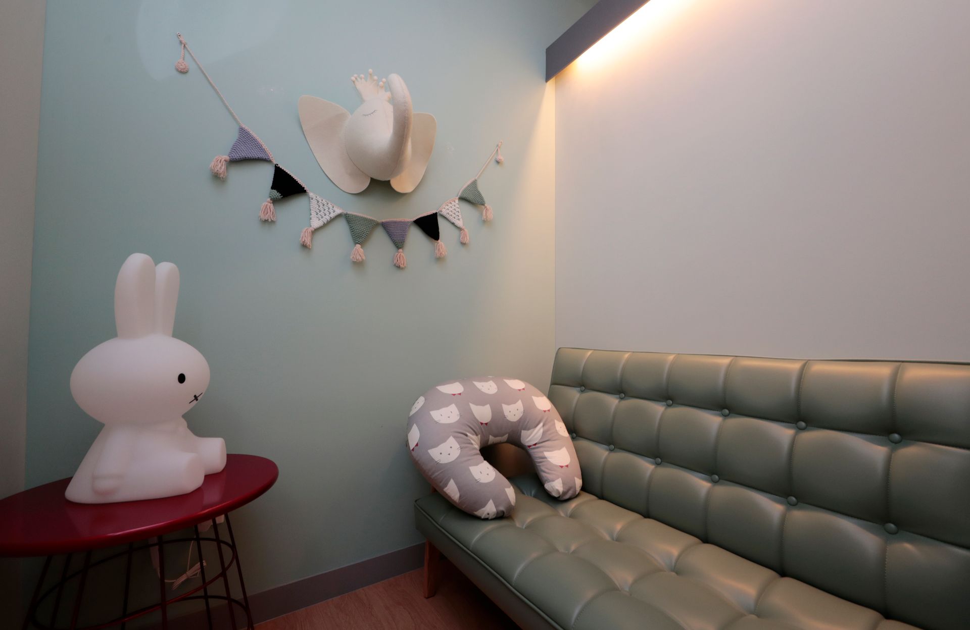 A charming nursery room featuring playful animal decor, soft lighting, and comfy seating.