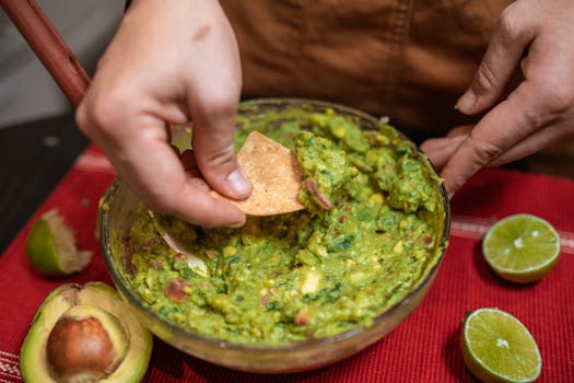 Close-up of homemade guacamole being served with tortilla chips and fresh lime.